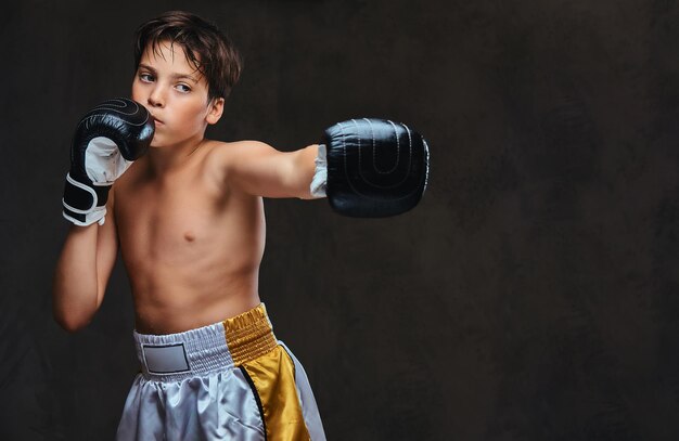 Handsome shirtless young boxer during boxing exercises, focused on process with serious concentrated facial.