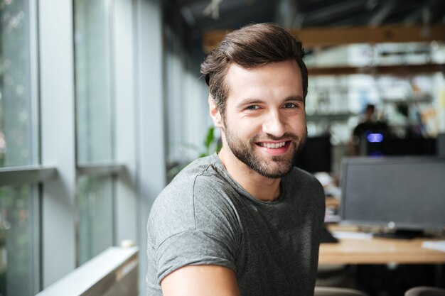 Handsome smiling young man sitting in office coworking