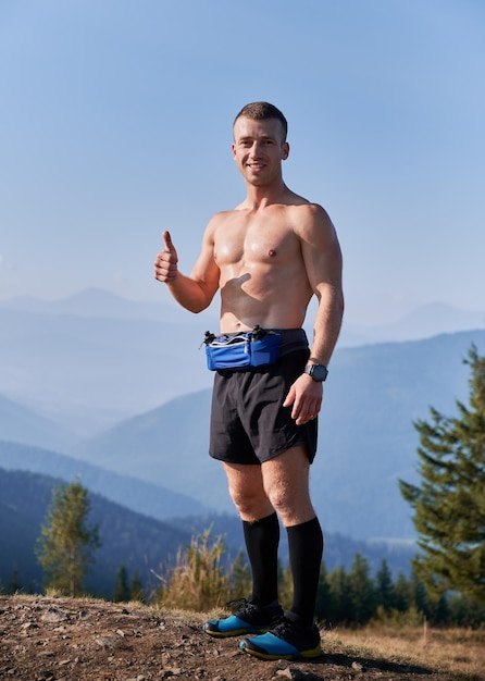 Handsome sports runner standing on top of mountain hill