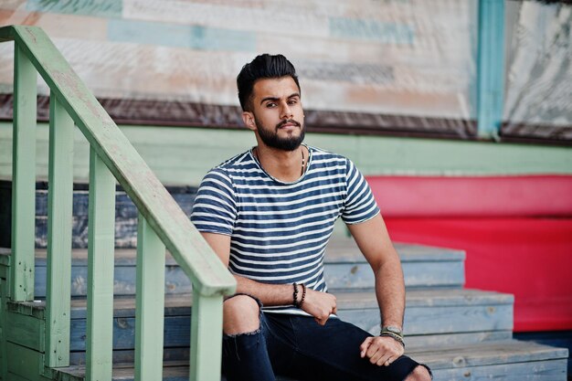 Handsome tall arabian beard man model at stripped shirt posed outdoor Fashionable arab guy