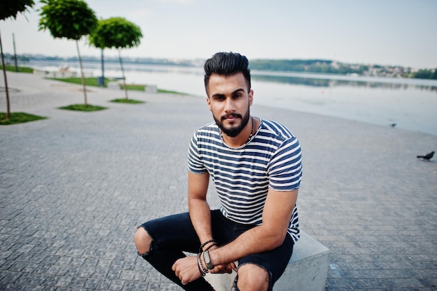 Handsome tall arabian beard man model at stripped shirt posed outdoor Fashionable arab guy