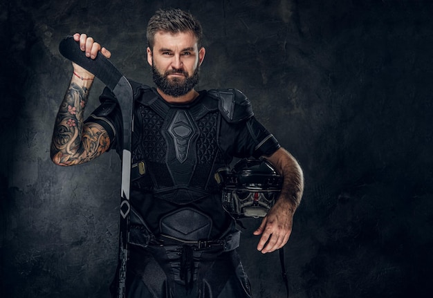 Free photo handsome tattooed hockey player in uniform is posing for photographer.