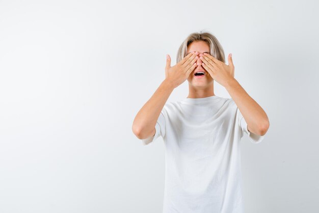 Handsome teen boy in a white t-shirt covering eyes