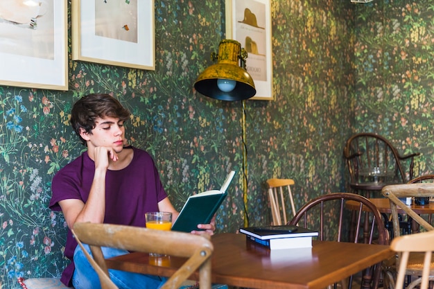 Handsome teenager reading in cafe