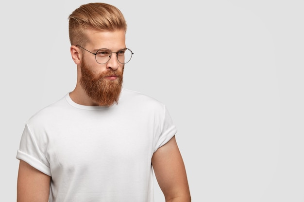 Free Photo handsome thoughtful stylish man has thick ginger beard, being deep in thoughts