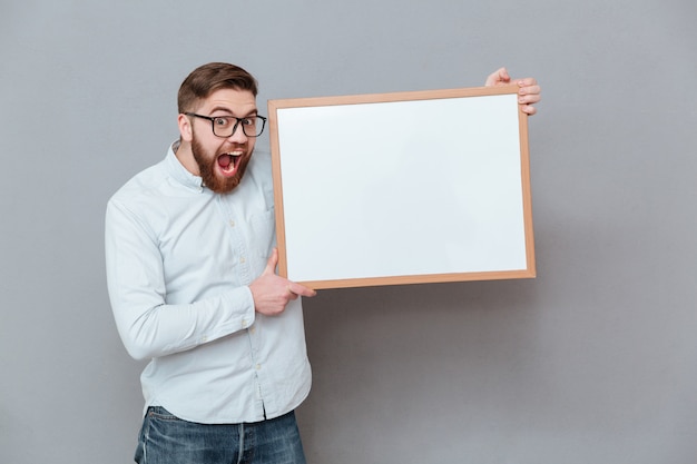 Free photo handsome young bearded businessman holding blank board