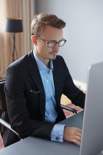 Free photo handsome young business man working with computer in office.