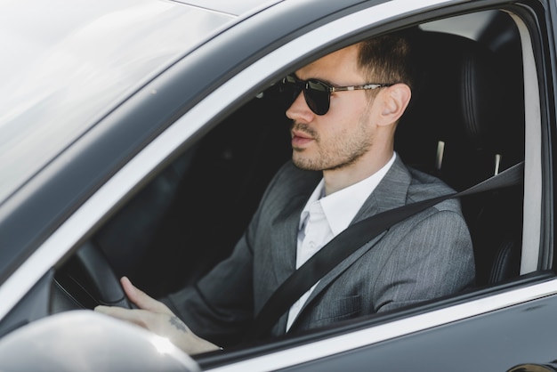 Free photo handsome young businessman driving car