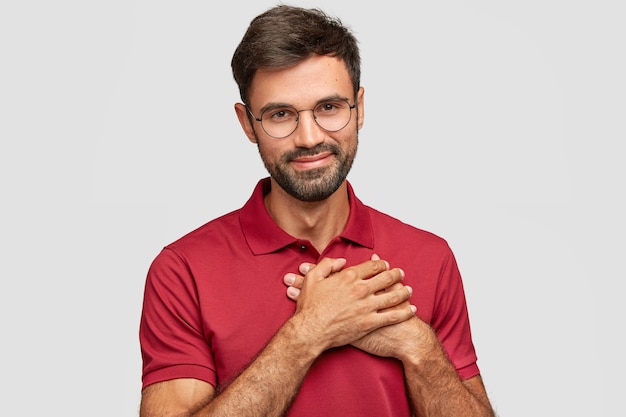 Handsome young emotional man posing against the white wall