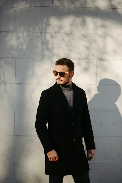 Handsome young fashion model posing on city streets.Outdoor fashion portrait, stylish man in elegant coat.