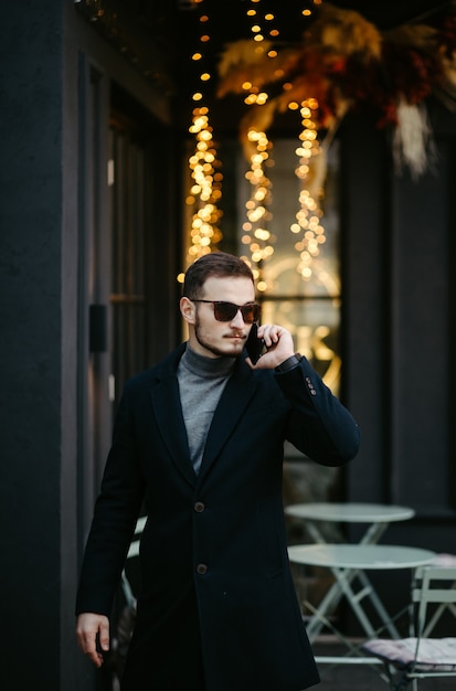 Free photo handsome young fashion model posing on city streets.outdoor fashion portrait, stylish man in elegant coat.