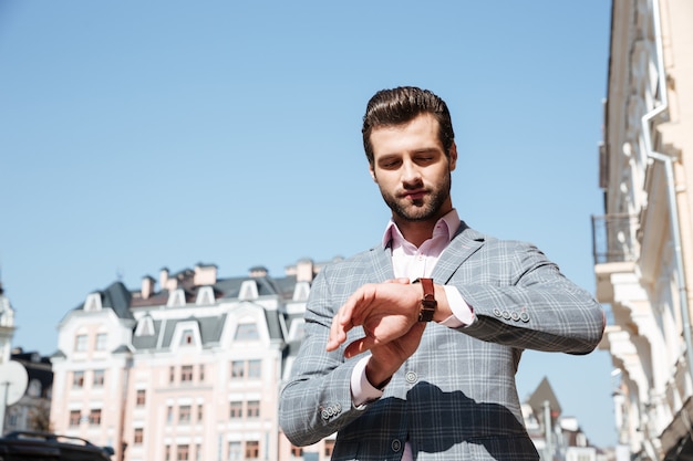 Free Photo handsome young man checking the time on his wrist watch