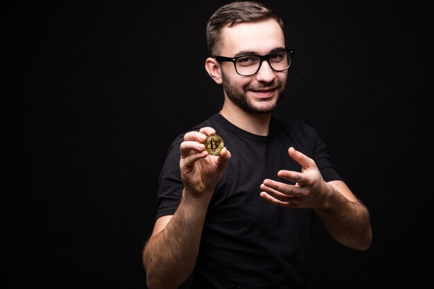 Handsome young man in glasses wear in black shirt present bitcoin isolated on black