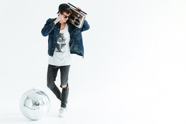 Handsome young man holding boombox near disco ball