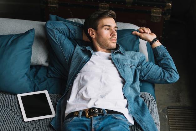 Free photo handsome young man lying on bed holding the pillow with hand