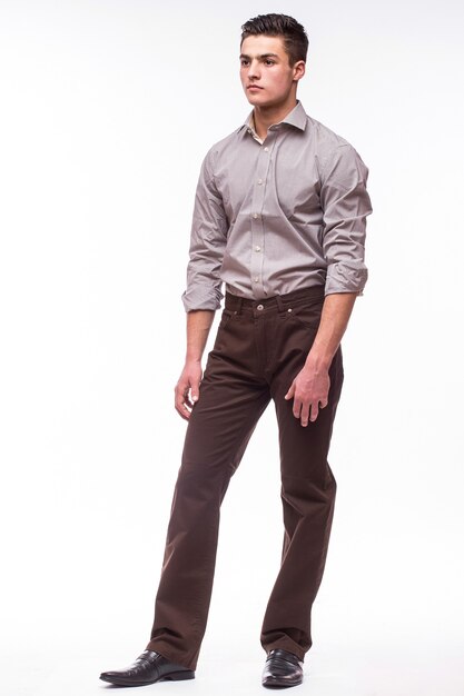 Handsome young man in shirt while standing against white wall