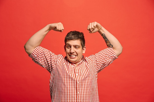 Free Photo handsome young man showing biceps expressing strength and gym concept, healthy life its good. young emotional surprised man standing at studio. human emotions, facial expression concept.