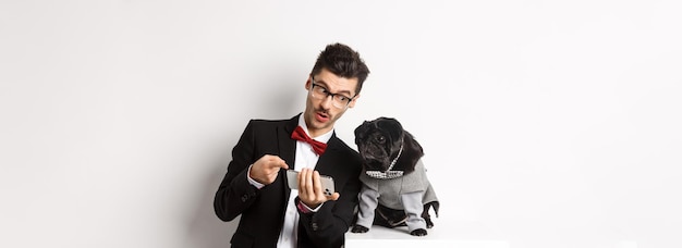 Handsome young man showing something on mobile phone to his dog owner shopping online with pet stand