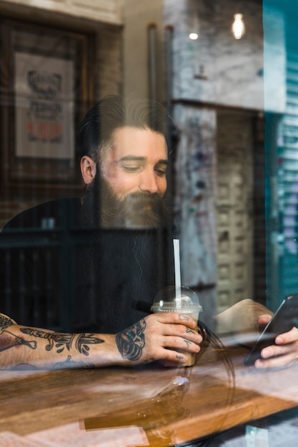 Handsome young man sitting in cafe using mobile phone