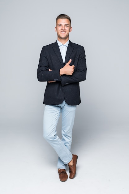 Free Photo handsome young man student businessman in jacket holds his arms crossed isolated on light grey wall