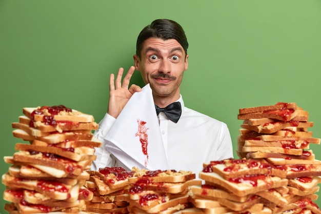 Free photo handsome young man surrounded by peanut butter jellly sandwiches