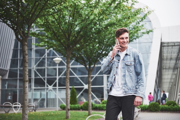 A handsome young man talking on the phone near the office space.