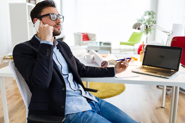 Free photo handsome young man using his mobile phone in the office.