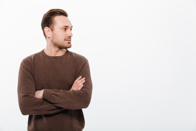 Handsome young man with arms crossed. Looking aside.