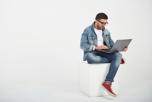 Handsome young man with laptop and check his timetable on white