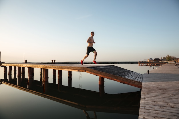 Handsome young sportsman running at the beach.