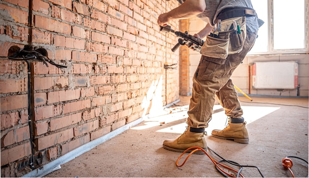 Free Photo handyman at a construction site in the process of drilling a wall with a perforator