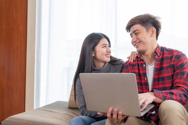 Happily young pretty woman and handsome man using laptop computer on the sofa in bedroom at home