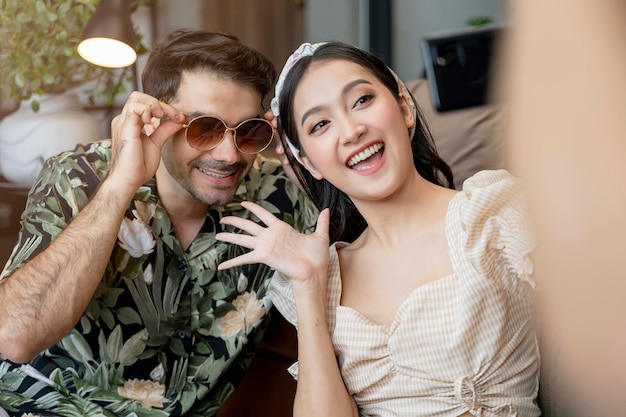 Happiness asian and caucasian marry travel couple wearing casual cloth enjoy unpack suitcase luggage and selfie together on the floor with joyful laugh smile travel and vacation concept