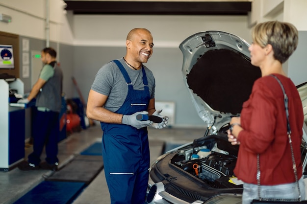 Free Photo happy african american auto repairman talking to customer in a workshop