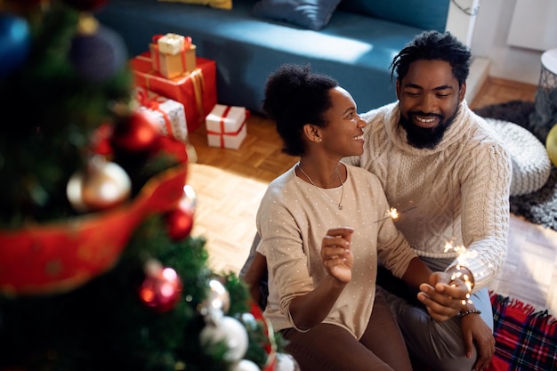 Happy African American couple having fun with sparklers on Christmas day at home