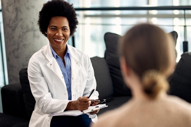 Happy African American doctor talking with female patient during a psychotherapy session