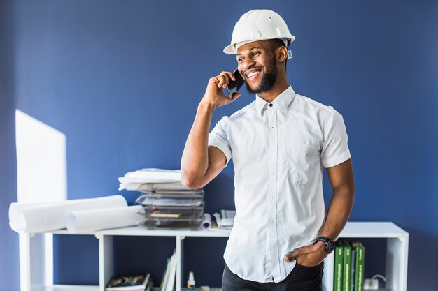 Happy african american engineer talking on mobile phone in the office