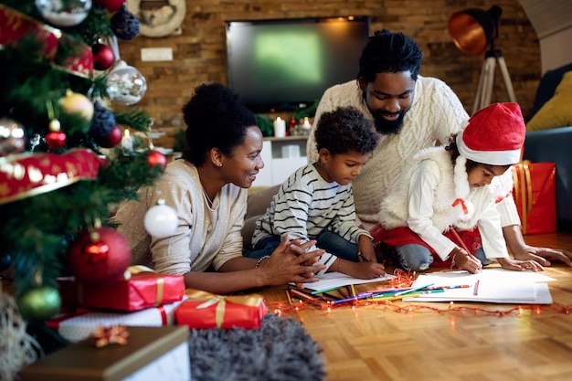 Happy African American family drawing on Christmas day at home