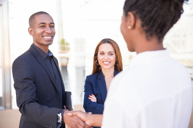 Happy African American male manager shaking hand of partner