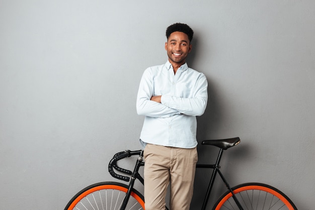 Happy african man standing near bicycle