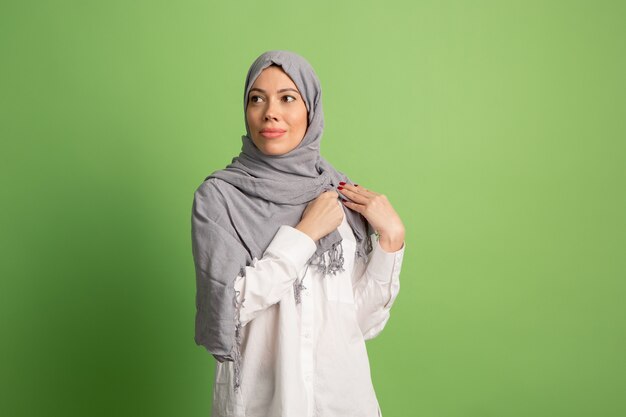 Happy arab woman in hijab. Portrait of smiling girl, posing at green studio background.