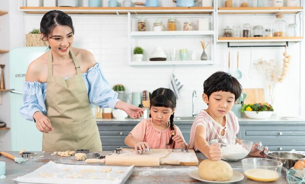 Happy Asian family making preparation dough and bake cookies in kitchen at home Enjoy family