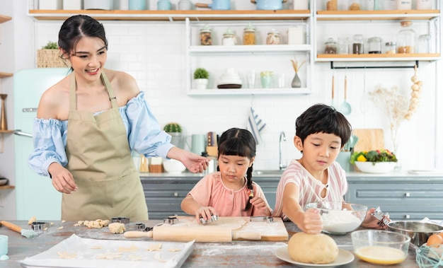 Happy Asian family making preparation dough and bake cookies in kitchen at home Enjoy family