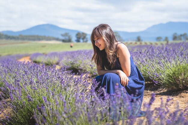 Happy Asian female in a long blue dress posing in the lavender field