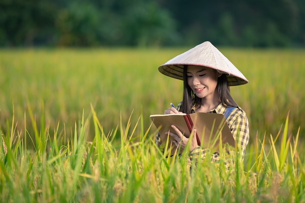 Happy asian female Write notes in rice fields