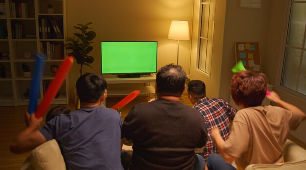 Happy asian friends or football fans watching soccer on Green Chroma Key Screen