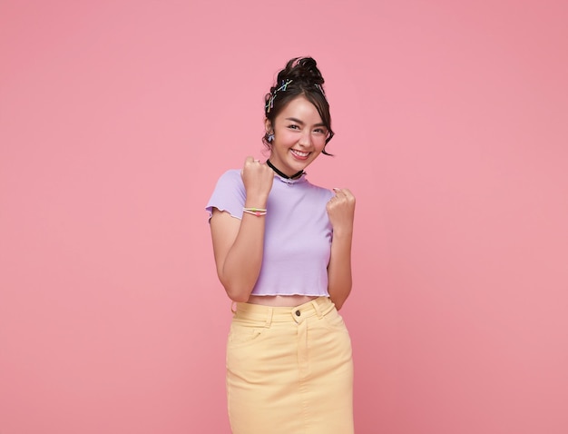 Free photo happy asian woman excited overjoyed standing with raised fists and shouting yeah