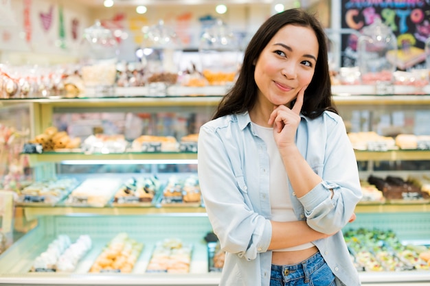 Happy Asian woman picking dessert in bakery store