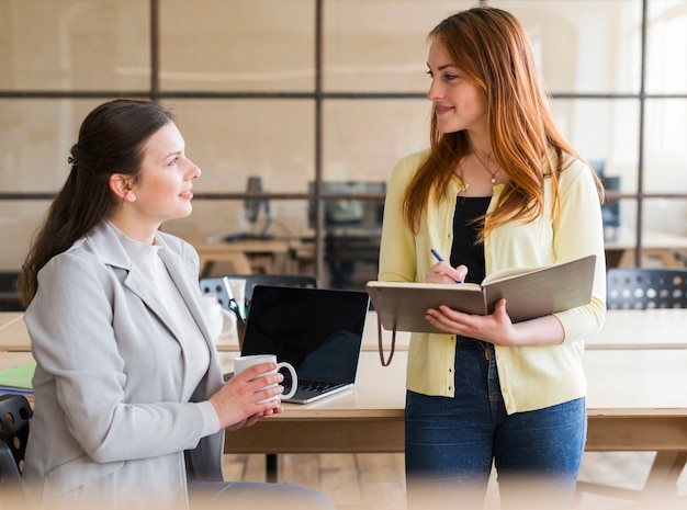 Happy attractive two woman working together at workplace