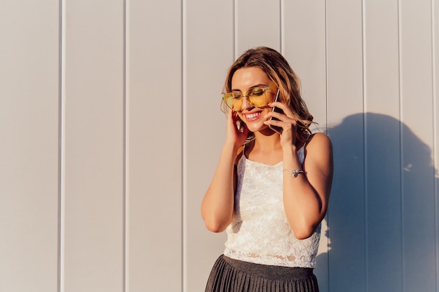 Happy attractive woman in yellow sunglasses having phone conversation